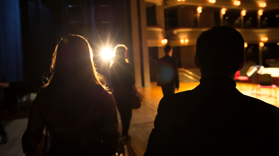 Silhouette of students walking onto stage of the Britten Theatre